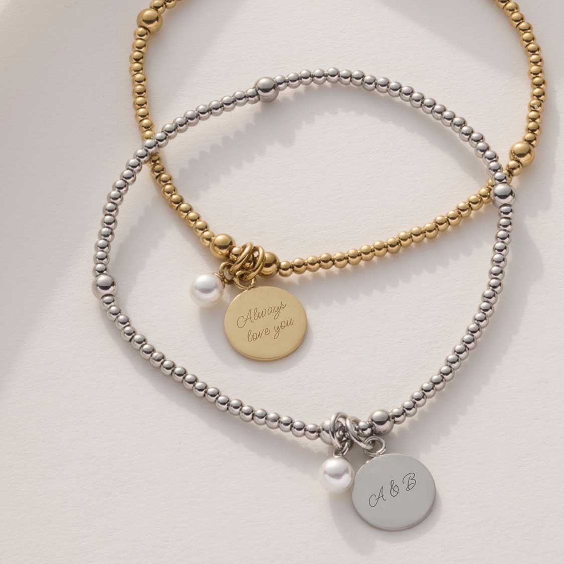 Zwei Armbänder DEBBY mit Perlen und gravierten Anhängern in Gold- und Silberfarben