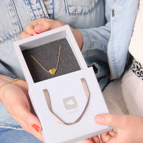 Frau hält Geschenkbox mit goldenem Halsketten-Anhänger offen