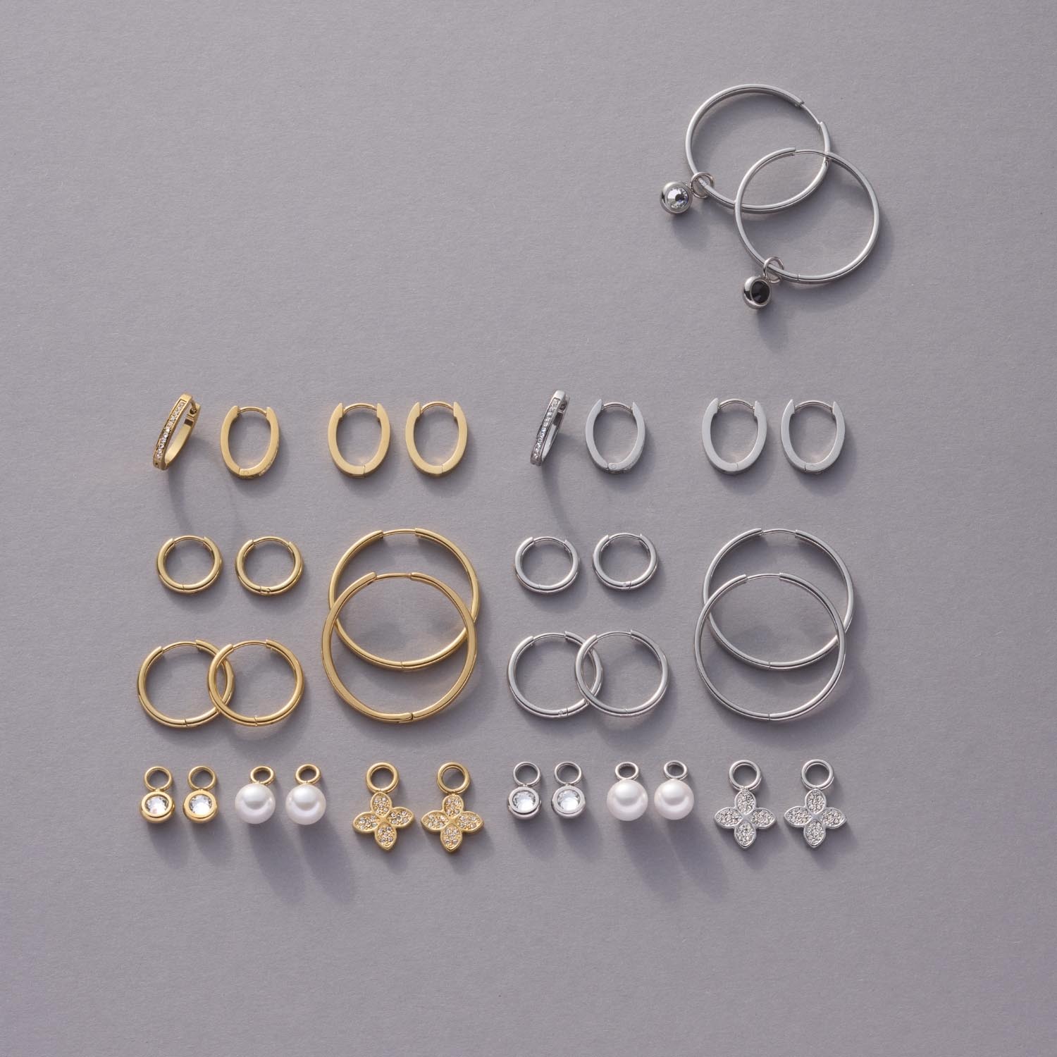 Schmuckset mit goldenen und silbernen Ringen und Anhängern in verschiedenen Größen auf grauem Hintergrund