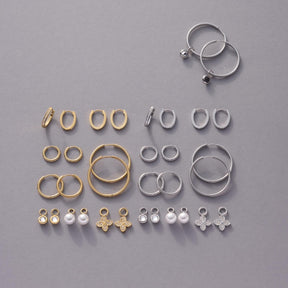 Schmuckset mit goldenen und silbernen Ringen und Anhängern in verschiedenen Größen auf grauem Hintergrund