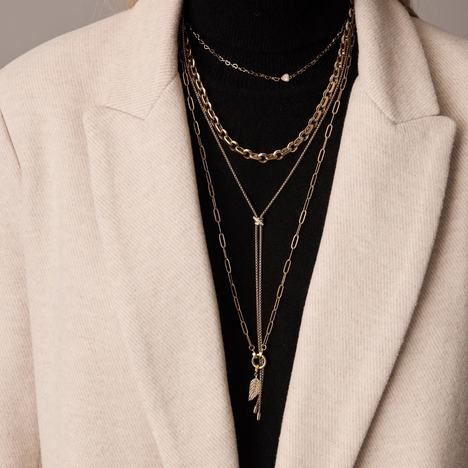 Halskette NALA 50 cm in Gold, mehrlagig um Hals getragen, über schwarzem Top und cremefarbener Jacke