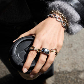 Hand mit Ring BELLE 19 gold, Armband und schwarzer Handtasche