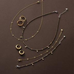 Armband ANNA CIAO in Gold- und Silbertönen mit Ringen und Schmuckstücken auf braunem Untergrund