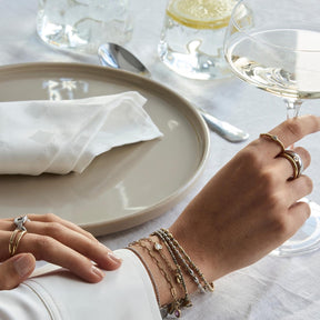 Hand mit mehreren goldenen Ringen am gedeckten Tisch