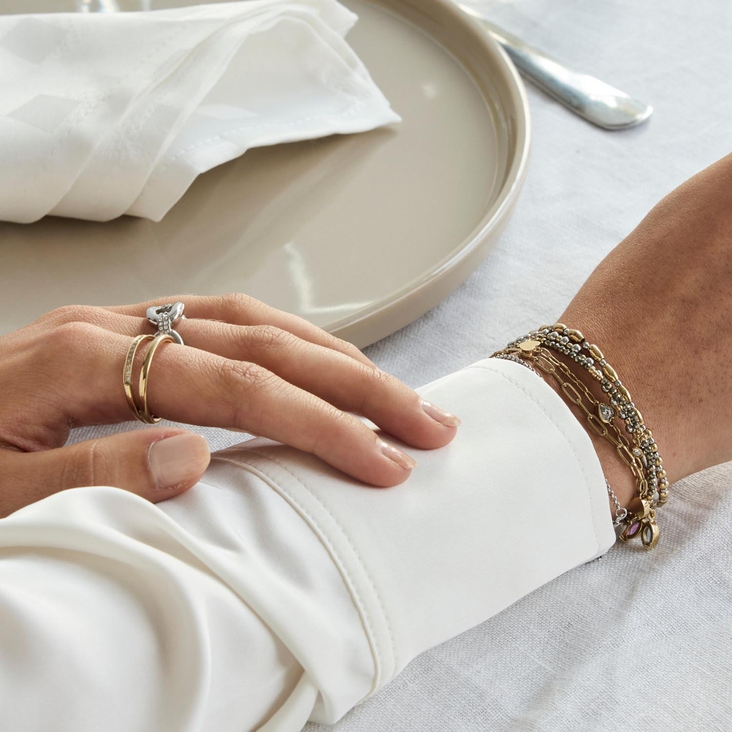 Hand traegt Ring TINI 18 gold CIAO mit Armband, gedecker Tisch