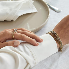 Hand traegt Ring TINI 18 gold CIAO mit Armband, gedecker Tisch