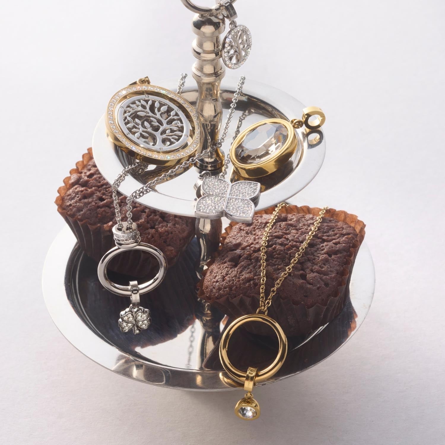 Halskette VERA mit verschiedenen Schmuckanhängern auf braunem Textil arrangiert
