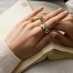 Hand traegt mehrere Gold-Ringe, offen auf Buch liegend