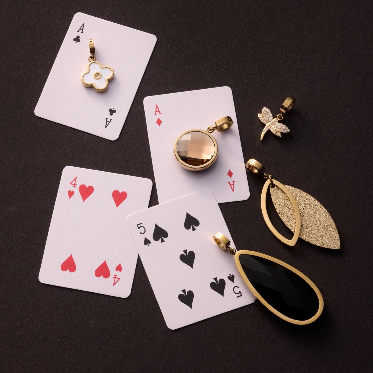 Anhänger DIANA Clip & Mix mit Spielkarten und goldfarbenen Accessoires auf schwarzem Untergrund
