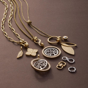 Goldene Schmuckanhänger und Ketten mit floralen Motiven und Schäkeln auf grauem Hintergrund