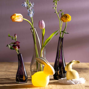 Violette Glasvase mit Schnittblumen in Dekosetting auf Holztisch