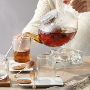 Teekanne MOON wird über Tasse gegossen, gedeckter Tisch mit Gebäck