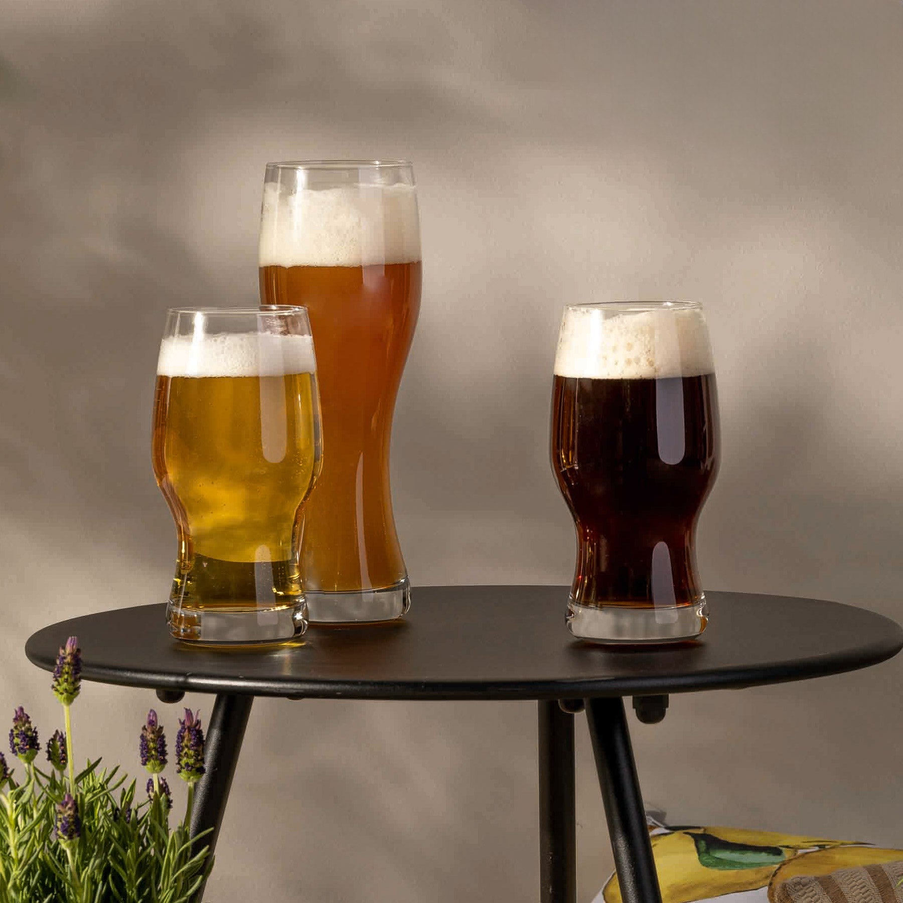 Drei gefüllte Biergläser auf schwarzem Tisch, Dekoration mit Pflanze