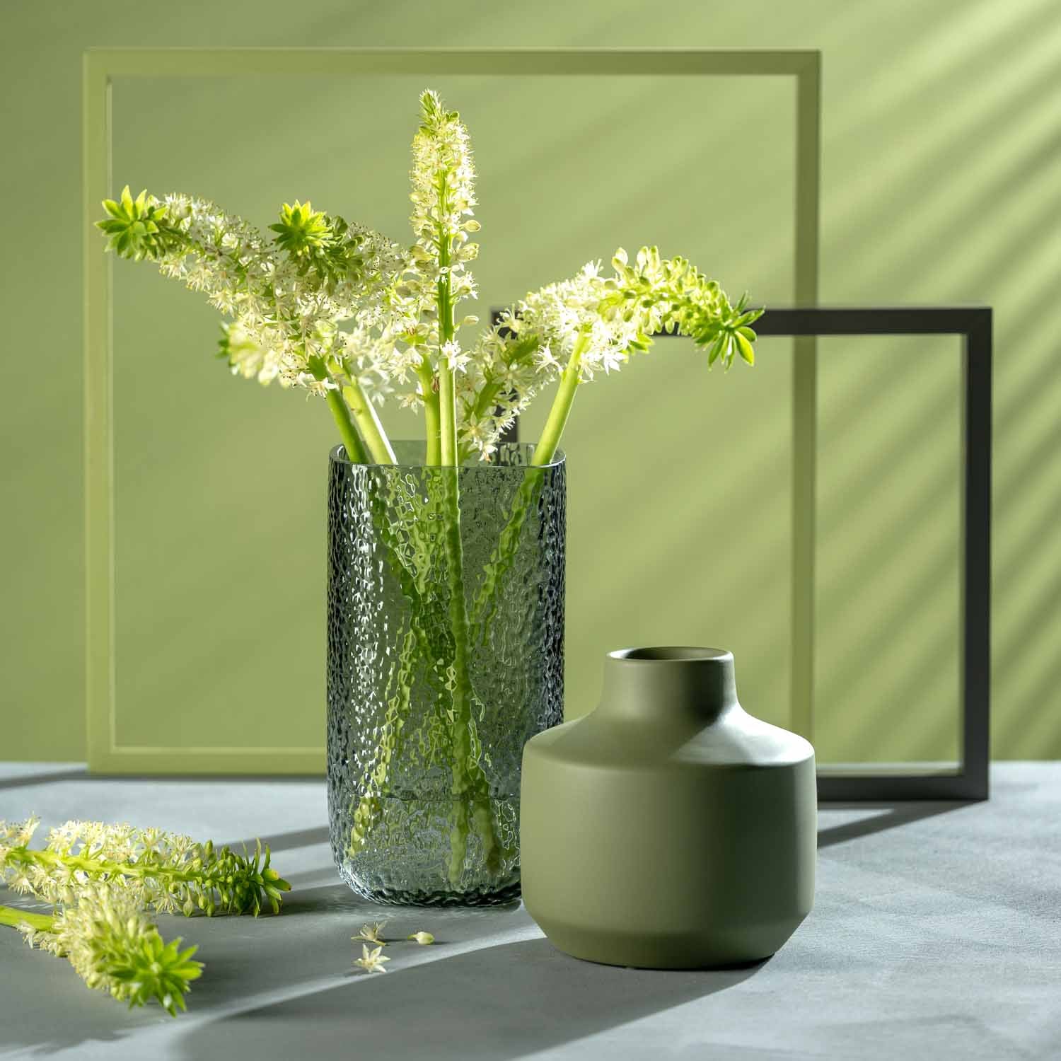 Vase MARTELLO 29 cm grau mit weißen Blüten gefüllt, daneben grüne Keramikschale