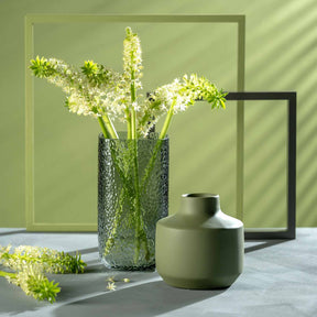 Vase MARTELLO 29 cm grau mit weißen Blüten gefüllt, daneben grüne Keramikschale