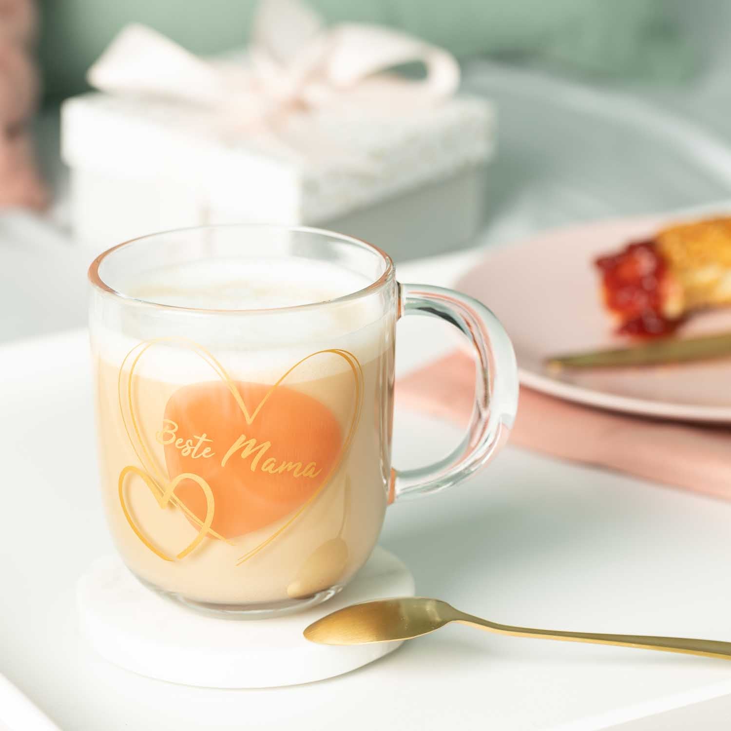 Glastasse EMOZIONE mit Gravur "Beste Mama" und Herzmotiv, gefüllt mit Getränk, auf gedecktem Tisch