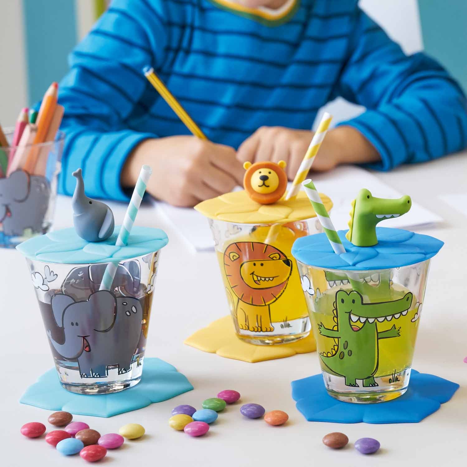 Kindertrinkset BAMBINI 3-teilig mit Elefant-, Löwen- und Krokodil-Motiven, Kind beim Malen, bunte Zuckerperlen auf dem Tisch