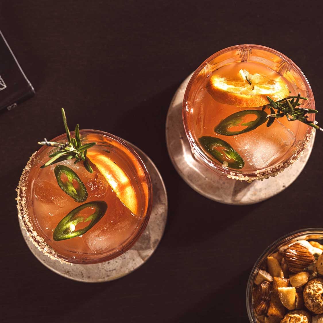 Trinkgläser SPIRITII NOVA mit Cocktails, Eiswürfeln und Jalapeño-Scheiben auf dunklem Untergrund
