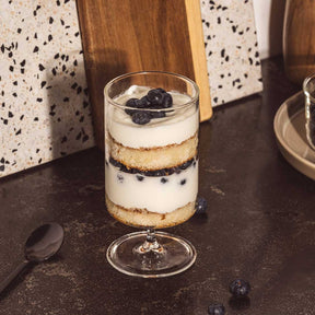 Trinkglas auf Fuß BASSO gefüllt mit Dessert, Blaubeeren und Creme auf dunkler Arbeitsplatte