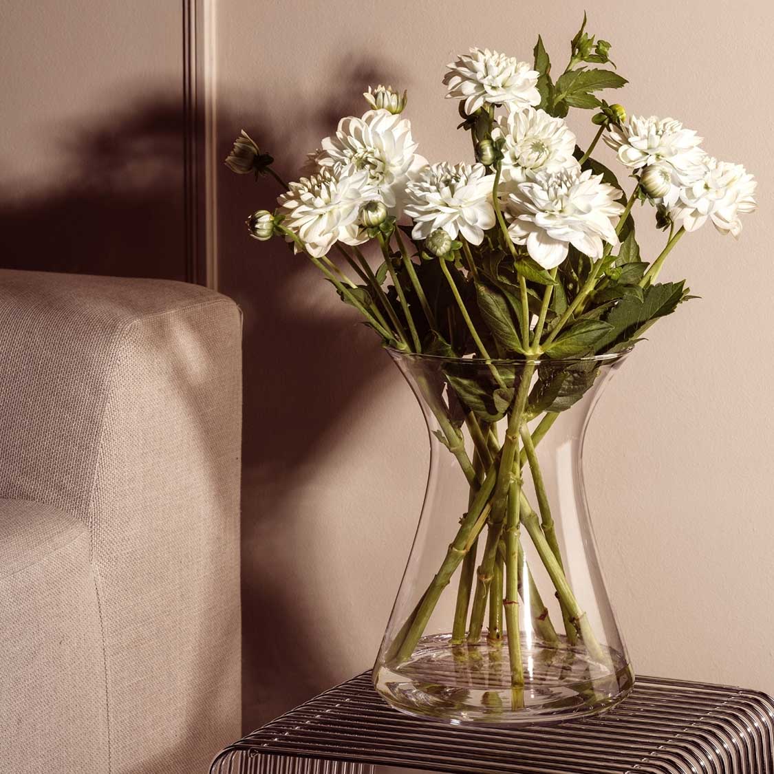 Vase GIA mit weissen Blüten in Wohnraum neben Sessel