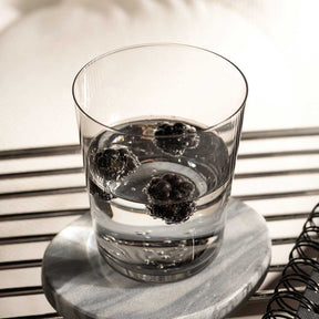 Trinkglas LEGGERO mit Wasser und Eiswürfeln auf grauem Untersetzer