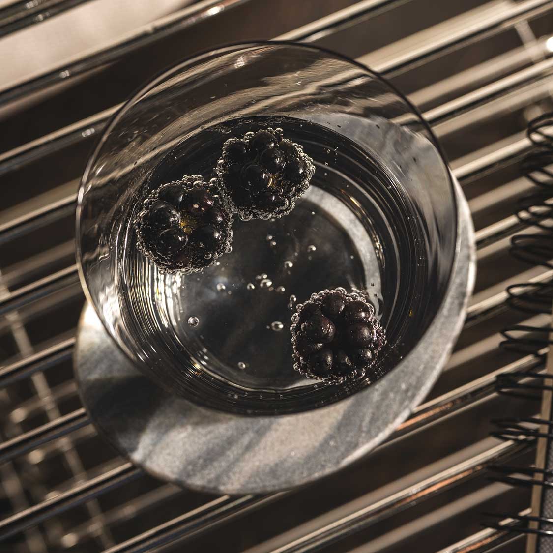 Trinkglas LEGGERO mit Wasser und Eiswürfeln auf gestreifter Oberfläche