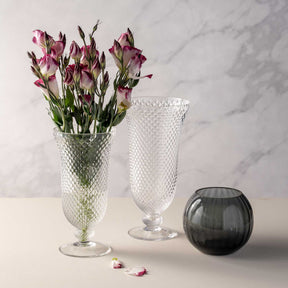 Drei Glasvasen mit rosa-weißen Nelken auf Marmortisch, darunter Kugelvase POESIA grau