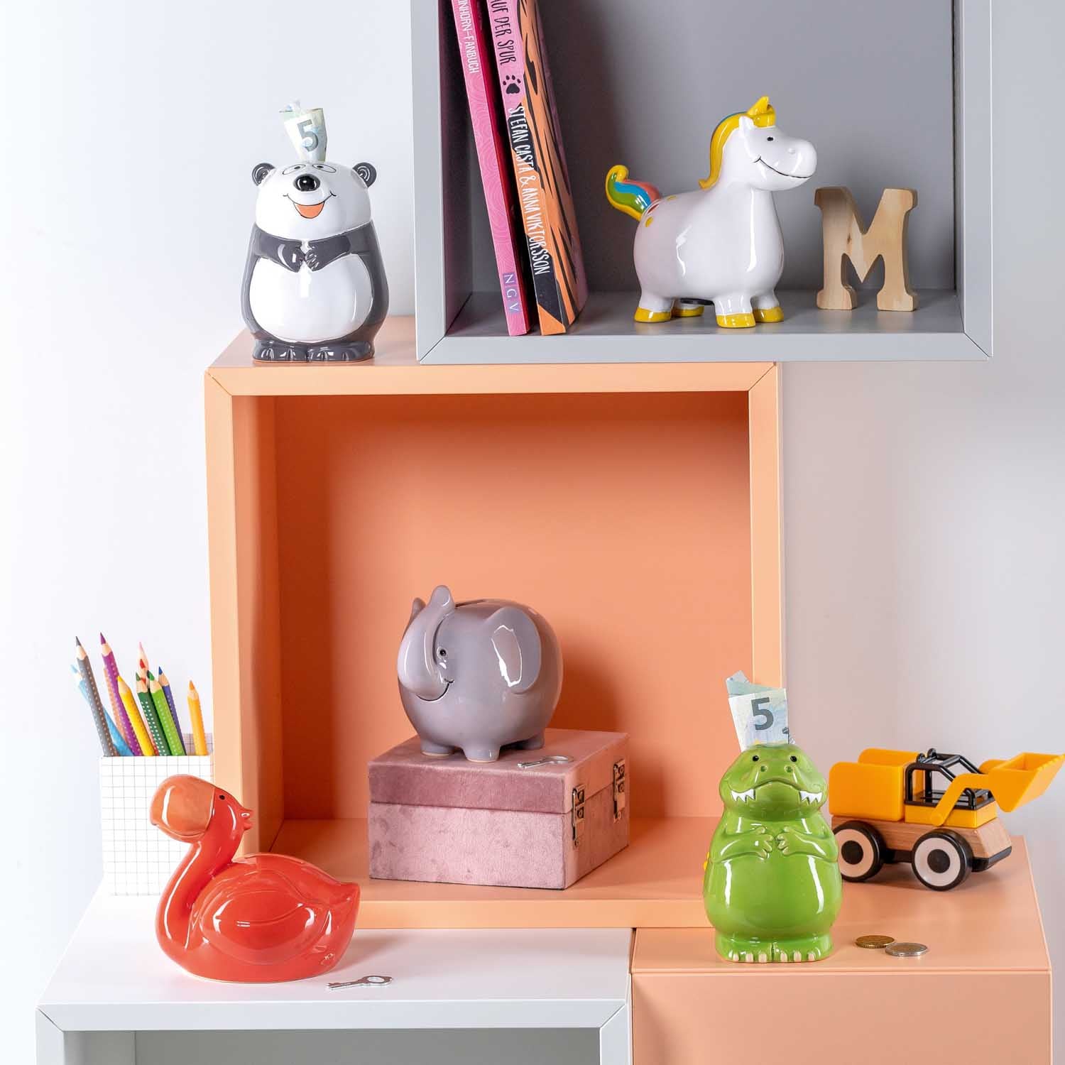 Rote Flamingo-Spardose in Kinderzimmer-Regal mit Spielzeugen und Büchern