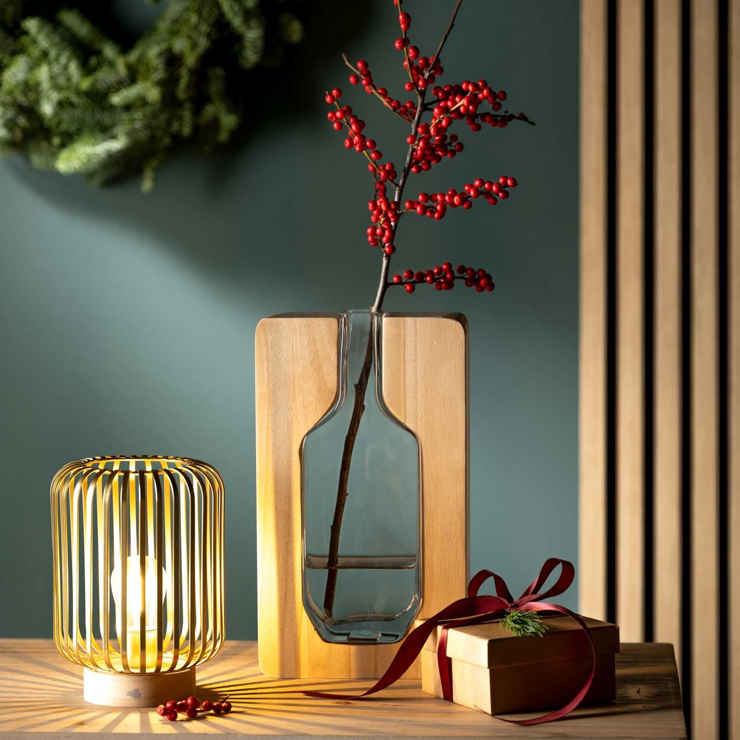 Holzvase AUTENTICO mit roten Beeren, goldene Lampe und Geschenkbox auf Tisch