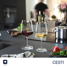 Weißweinglas CESTI und Rotwein­glas auf gedecktem Küchen­tisch mit Gemüse