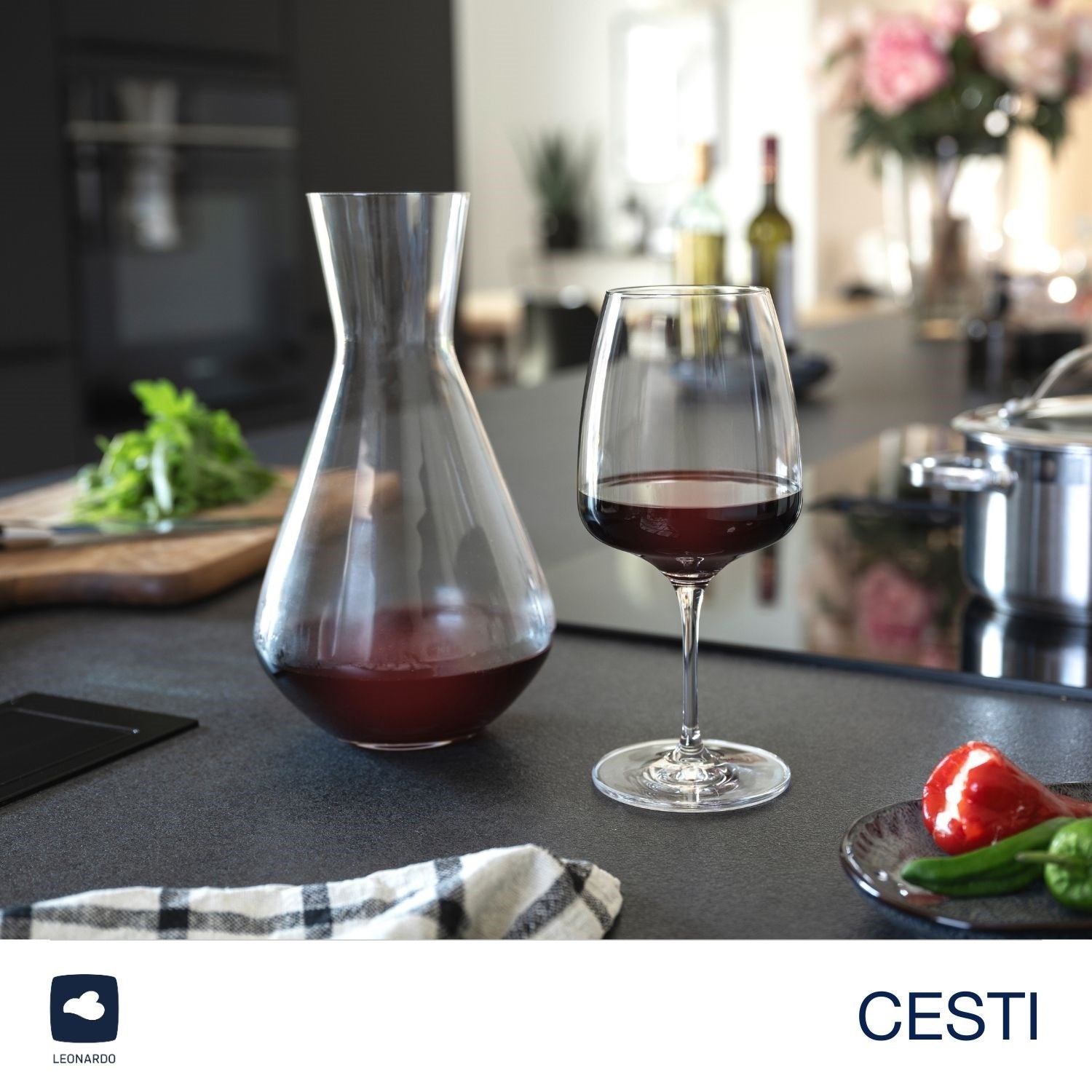 Weinset CESTI auf dunkler Küchentheke mit Rotwein, Dekoration und Blumen