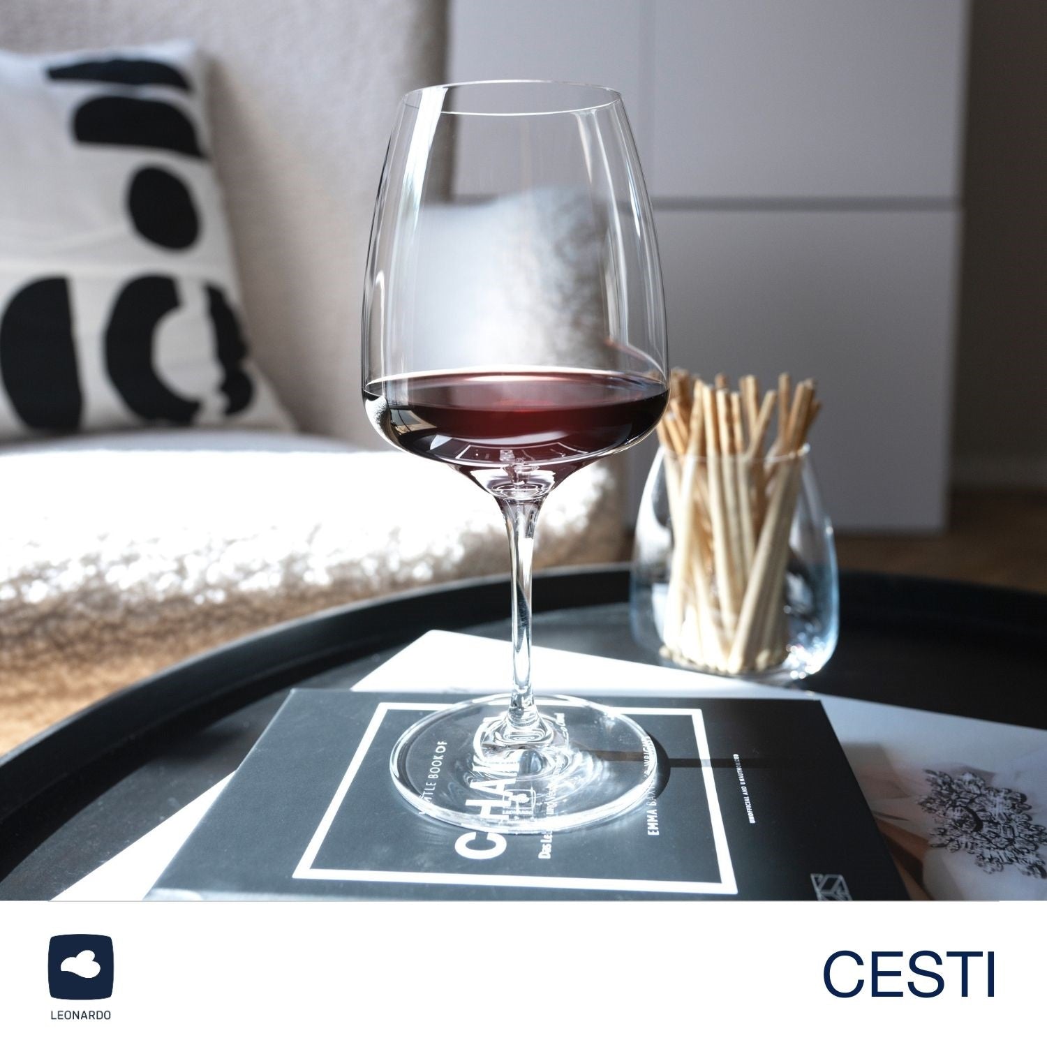 Weinset CESTI mit gefülltem Kelchglas auf schwarzem Tablett, Streichhölzer und Kissen im Hintergrund