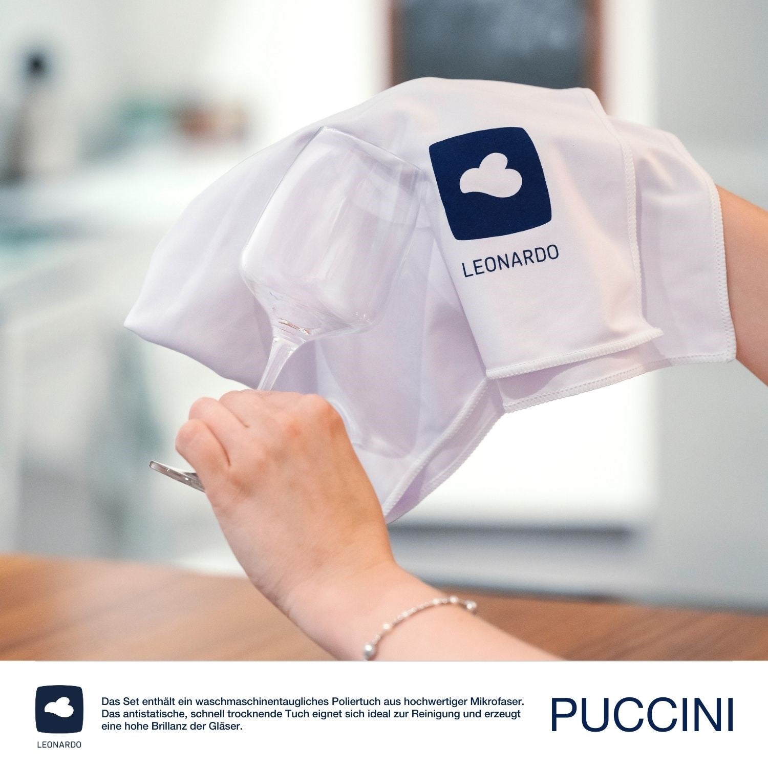 Hand hält Weißweinglas PUCCINI mit Poliertuch und Leonardo-Logo