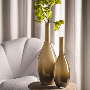 Braune Vase BEAUTY mit grünen Pflanzen im hellen Wohnzimmer neben weißem Sessel