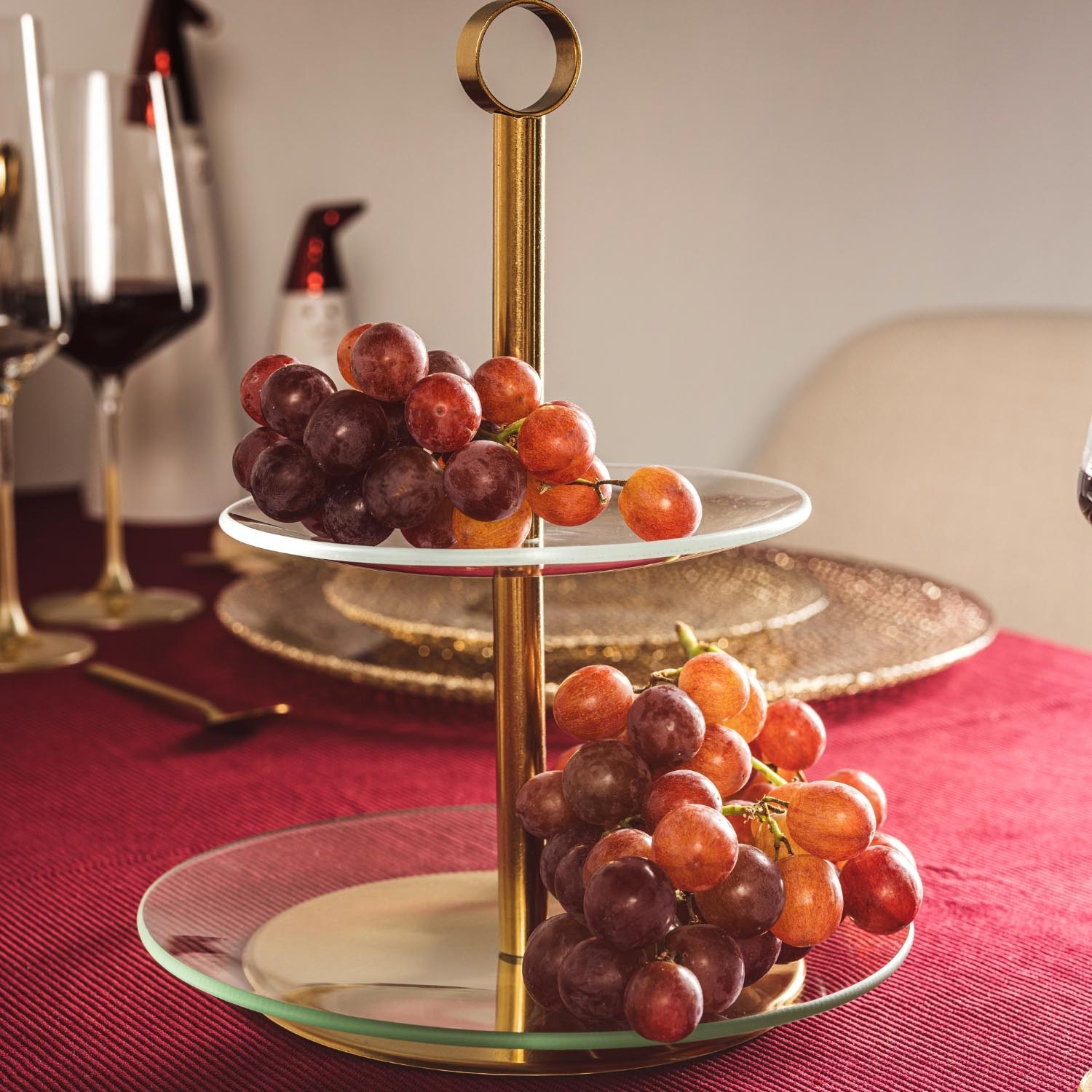 Etagere CENA gold mit roten Trauben auf gedecktem Tisch mit Wein
