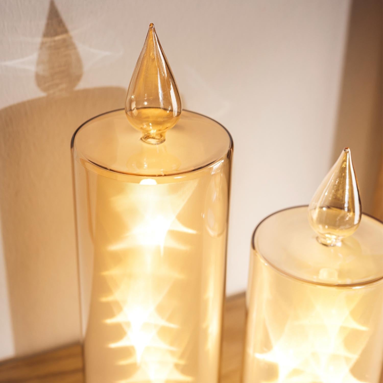 LED Kerze RIPOSO in Gold mit brennendem Licht, mehrere Kerzen nebeneinander