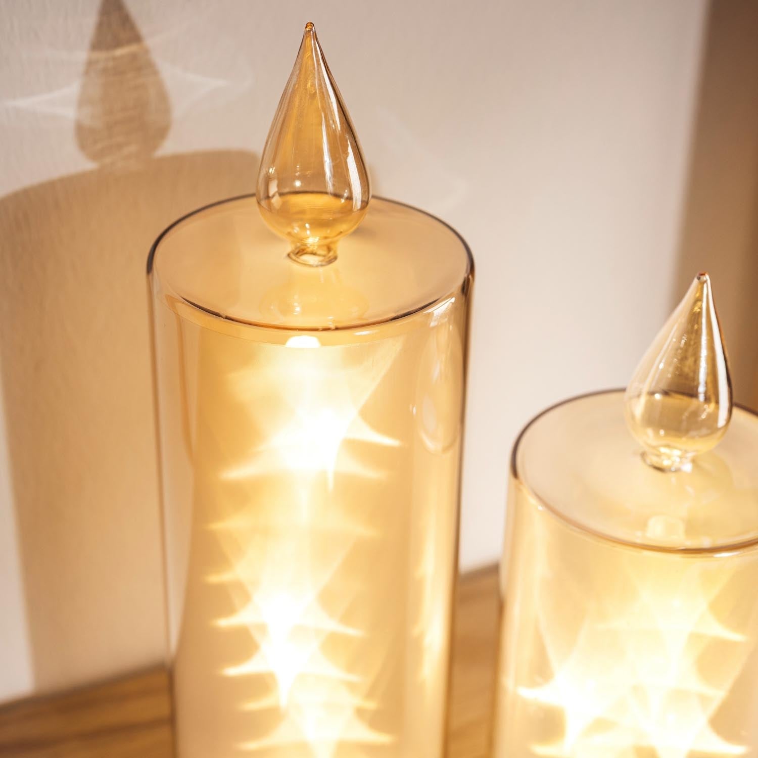 LED Kerze RIPOSO in Gold mit brennender Flamme auf Holzoberfläche