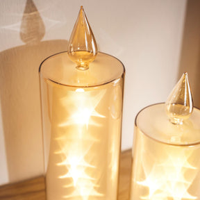 LED Kerze RIPOSO in Gold mit brennender Flamme auf Holzoberfläche