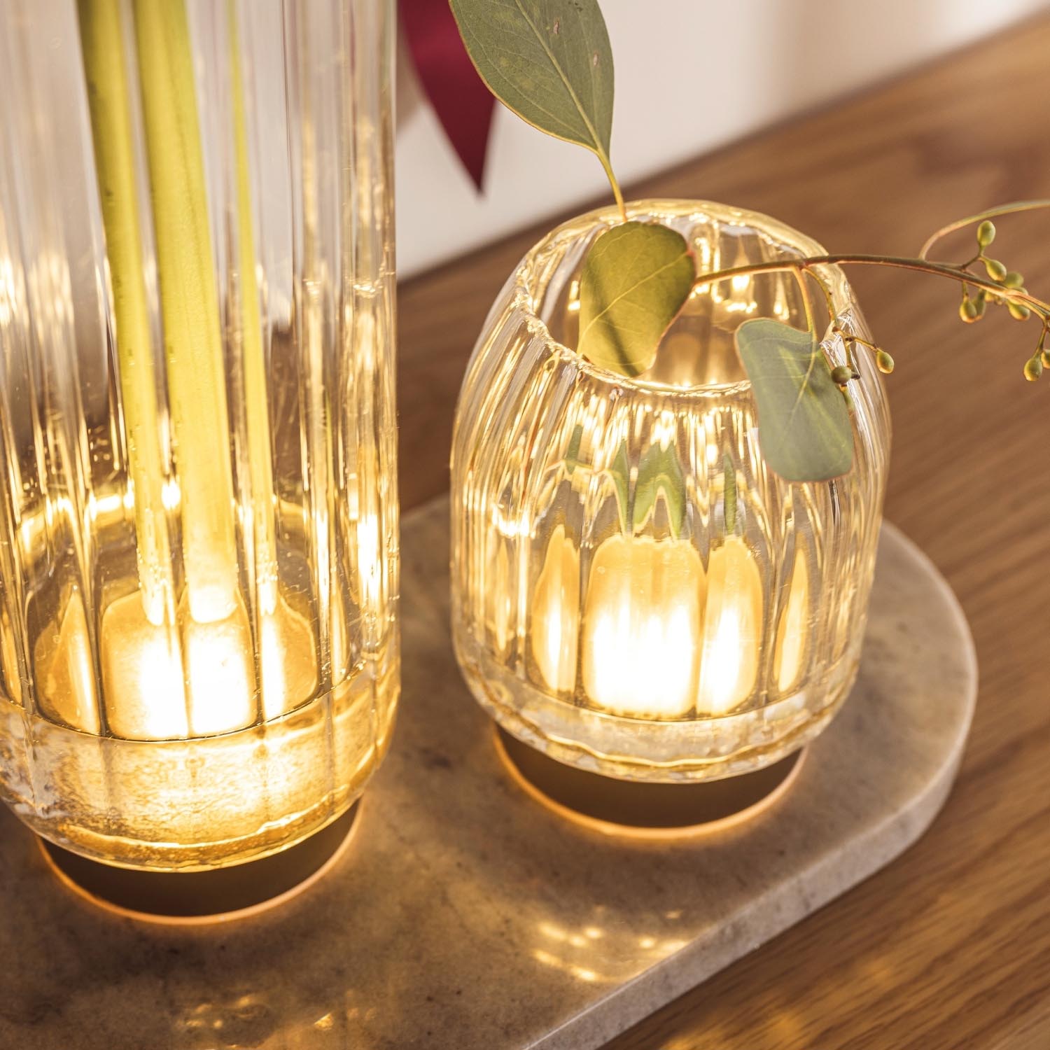 LED Vase RIPOSO mit Blättern auf Holzoberfläche, warm beleuchtet
