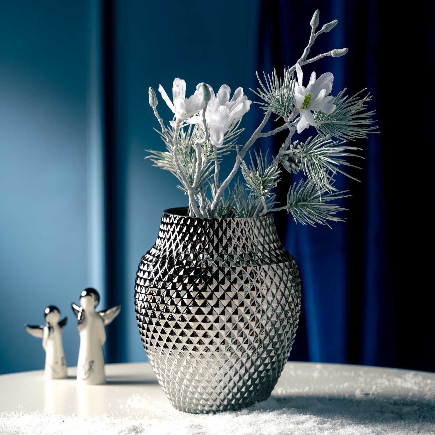 Weiße Magnolie in strukturierter Vase mit Dekofiguren und blauem Hintergrund