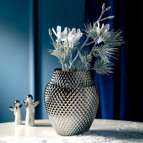 Weiße Magnolie in strukturierter Vase mit Dekofiguren und blauem Hintergrund
