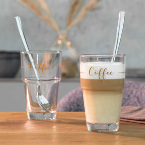 Becher SOLO mit Kaffeegetränk, Glas Wasser und Strohhalmen auf Holztisch