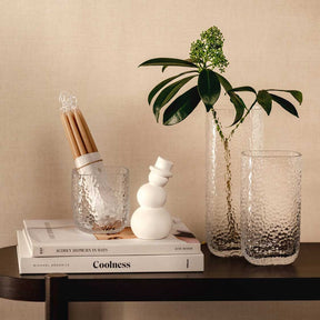 Tischlicht MARTELLO auf schwarzem Tisch mit Büchern, Kerzen und Pflanze in Vase