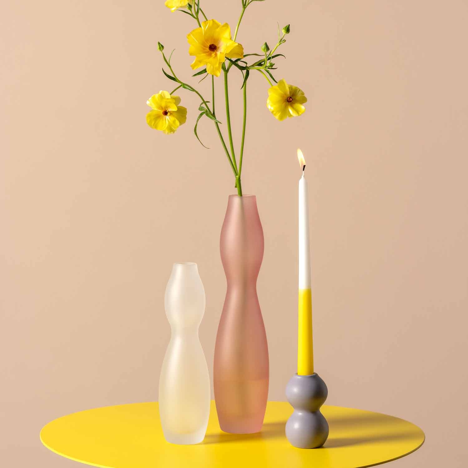 Keramikleuchter VIVACE mit gelbem Blumenstrauß und brennender Kerze auf gelbem Tisch