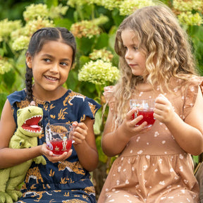 Zwei Kinder mit Dinosaurier-Tassen im Garten
