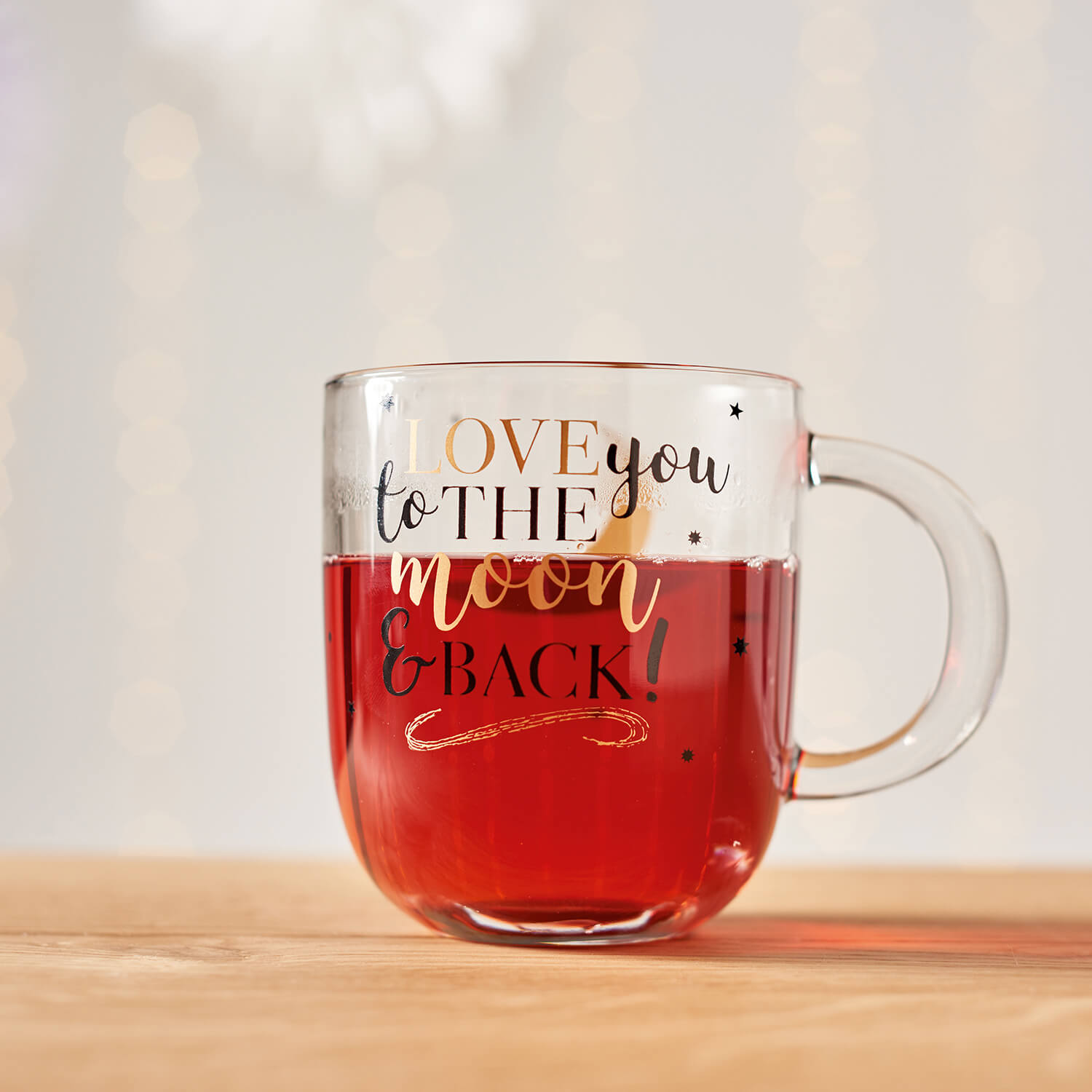 Tasse EMOZIONE mit rotem Inhalt und "Love you to the moon and back" Schriftzug auf Holztisch