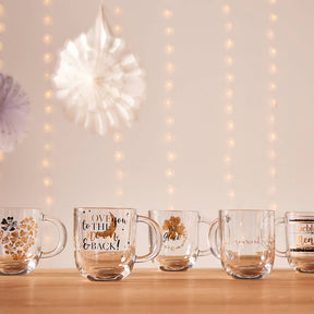 Mehrere Glastassen mit verschiedenen Motiven auf Holztisch, dekorativ arrangiert