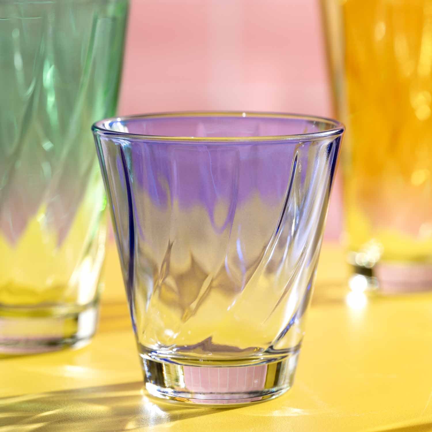 Trinkglas TWIST 215 ml in mehrfarbigem Glas auf gelbem Untergrund mit weiteren farbigen Glaesern im Hintergrund