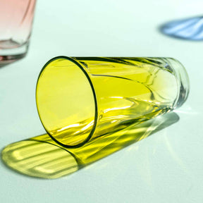 Gelbes Trinkglas TWIST 300 ml liegt auf weißer Oberfläche mit Schatten