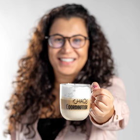 Frau mit Brille haelt Glastasse UFFICIO 400 ml mit Aufdruck CHAOS COORDINATOR